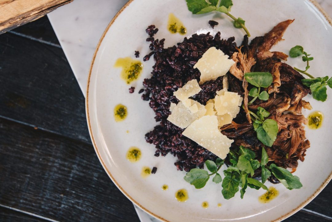 Foto de um prazo com arroz negro e costata di manzo.