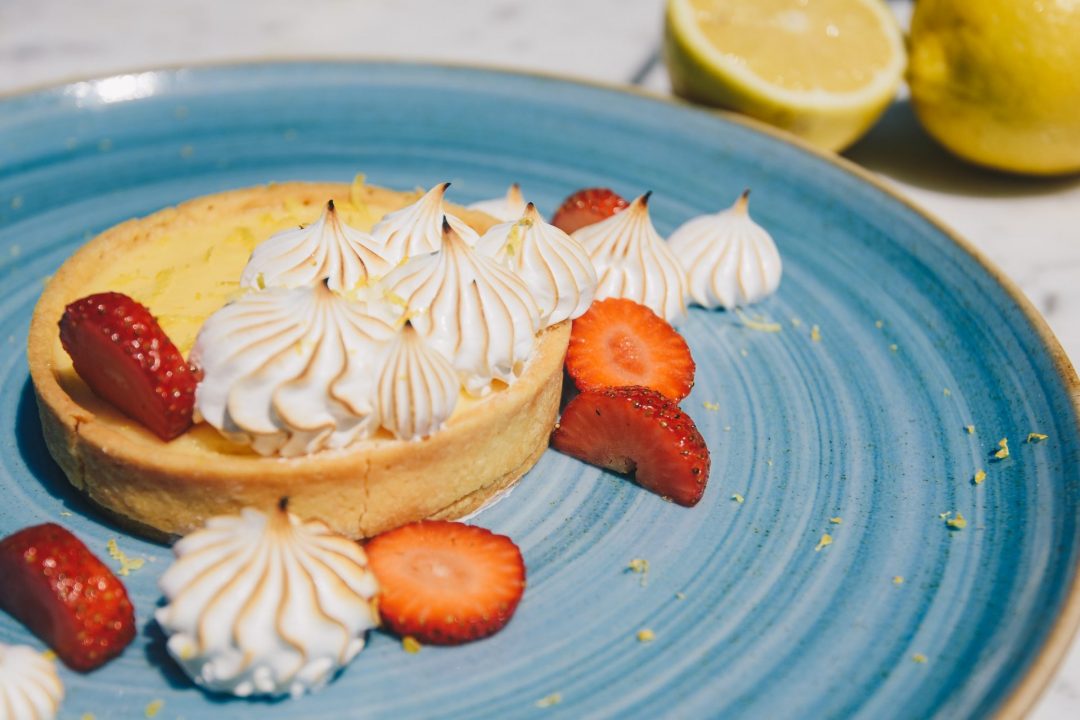 Foto de uma torta de limão com suspiros e morangos.